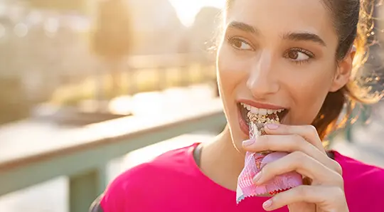 Woman eating granola bar with cold-seal packaging