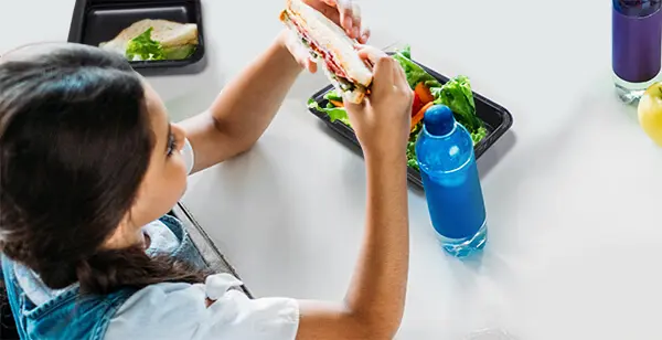 girl eating from a thermoformed food tray at school